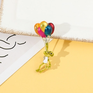 Détail d'une mignonne broche grenouille ballon avec émail coloré et finition dorée