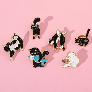 Flat lay of six creative cartoon cat enamel pins on a soft pink background