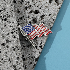 Nahaufnahme der US-Flaggen-Brosche mit Strasssteinen und Emaille auf grauem Stein