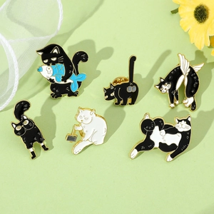 Detail of six creative cartoon cat enamel pins featuring a cat holding fish on green background