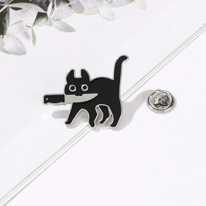 Détail d'un pin's chat noir émaillé avec couteau et fermoir en métal argenté brillant
