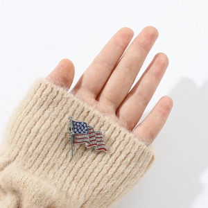Detailansicht einer funkelnden US-Flaggen-Brosche an einem beigen Strickpullover-Ärmel