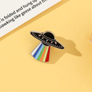 Macro detail of UFO enamel pin with rainbow beam on bright yellow background
