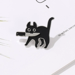 Macro d'un pin's en émail chat noir créatif avec couteau sur fond de carte blanche