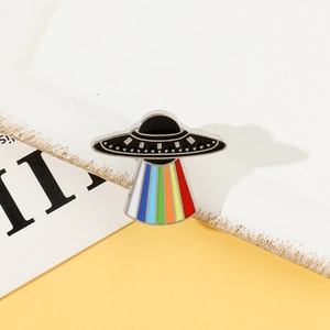 Macro detail of UFO enamel pin with vibrant rainbow light beam and black dome finish