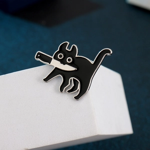 Détail macro du pin's en émail chat noir avec couteau sur support blanc moderne