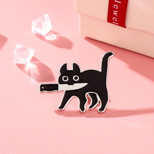 Gros plan détaillé d'un pin's chat noir en émail tenant un couteau sur fond rose doux