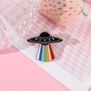 Macro detail of UFO enamel pin showing a vibrant rainbow beam with smooth metal finish