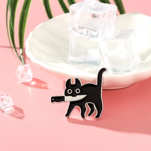 Détail d'un pin's émaillé de chat noir mignon avec couteau sur fond rose esthétique