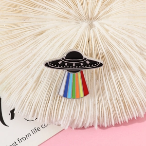 Macro detail of cartoon UFO enamel pin with vibrant rainbow beam and silver metal edges