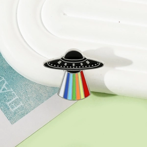 Detail of UFO enamel pin with rainbow beam and silver metallic edges on a display stand