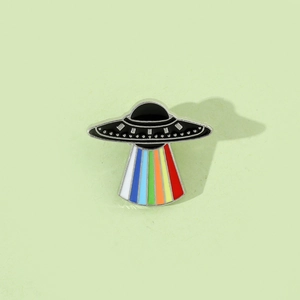 Macro shot of cartoon UFO enamel pin with vibrant rainbow beam and silver metallic edges