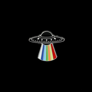Macro detail of UFO brooch with vibrant rainbow light beams on black background