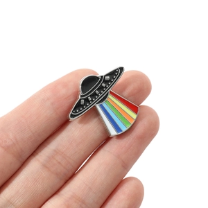 Cartoon UFO enamel pin with vibrant rainbow light beam on a minimalist metal badge