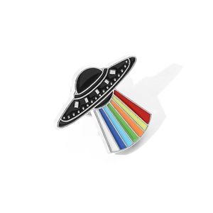 Close-up of UFO enamel pin with vibrant rainbow light beam on a white background