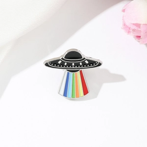 Macro detail of UFO enamel pin with colorful rainbow light beam on metal badge