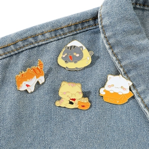 Set di quattro spille smaltate a forma di gatto cartone animato su giacca di jeans
