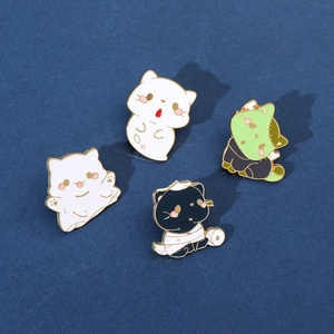 Close-up of four Halloween enamel pins featuring ghost, mummy, and Frankenstein cat designs
