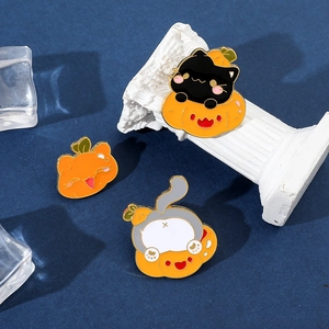 Detailed view of Halloween cat enamel pins featuring pumpkin and feline motifs on props