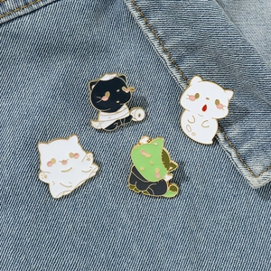 Funny Halloween cat enamel pins featuring mummy, ghost and zombie kittens on denim