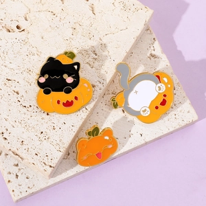 Detail of creative Halloween enamel pins featuring black cat on pumpkin and kitten badge