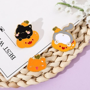 Detailed close-up of three enamel cat pumpkin brooches on a rustic textured background