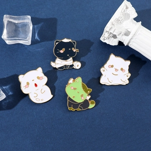 Detail of four creative Halloween cat enamel pins showing ghostly kittens on a blue background