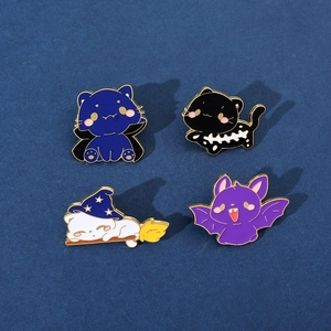 Detailed close-up of four Halloween cat enamel pins with gold plating and vibrant colors