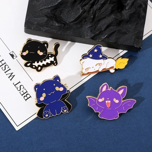 Close-up of four Halloween enamel pins featuring cute cats in spooky costumes