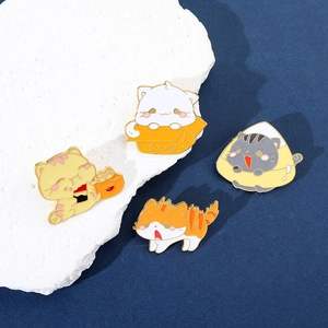 Set di quattro spille in smalto con gatti carini in pose creative su pietra