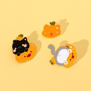 Detail view of three creative Halloween cat and pumpkin enamel pins on a yellow background