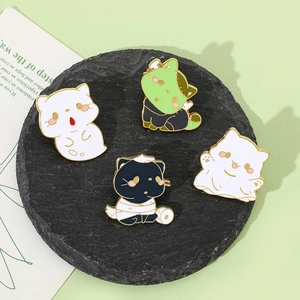 Close-up of four cat enamel pins with Halloween ghost and monster themes on a stone tray
