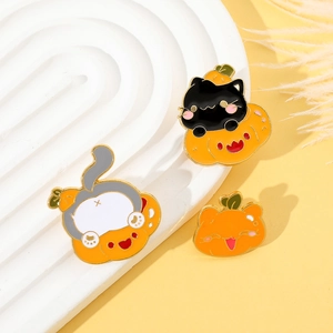 Macro shot of Halloween black cat and pumpkin enamel pins on a white platform