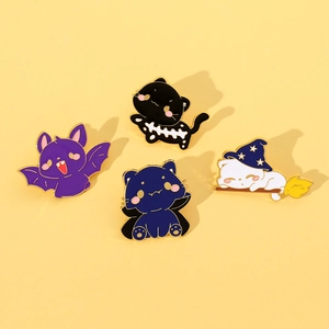 Detail view of four Halloween enamel cat pins with witch hats and bat wings on yellow background