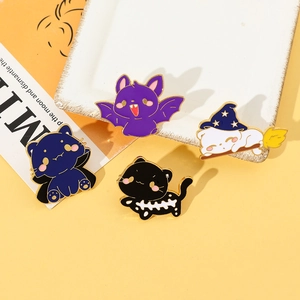 Detailed close-up of four Halloween cat and bat enamel pins on a white decorative tray