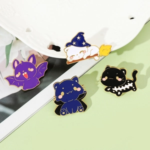 Close-up of four Halloween cat enamel pins featuring wizard and bat motifs on a ceramic dish