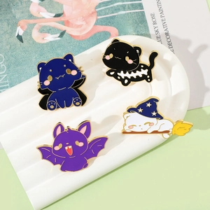 Detail of four Halloween cartoon cat enamel pins on a white decorative display tray