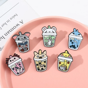 Group view of six cute animal-themed bubble tea enamel pins on a pink ceramic tray