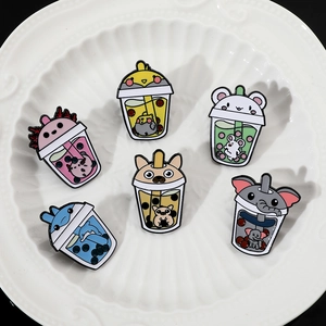 Detailed view of six cute animal milk tea enamel pins on a white decorative ceramic plate