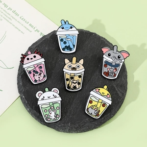 Detailed close-up of cute animal bubble tea enamel pins on black stone board