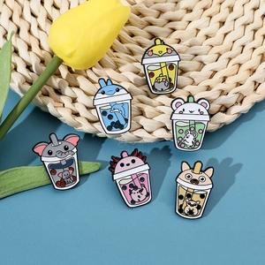 Detailed view of six enamel pins featuring cute animals in bubble tea cups on a mat