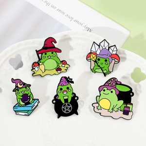 Set of five cartoon wizard frog enamel pins displayed on a decorative ceramic white plate