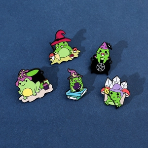 Detailed close-up of 5 magic-themed cartoon frog enamel pins on a dark blue background