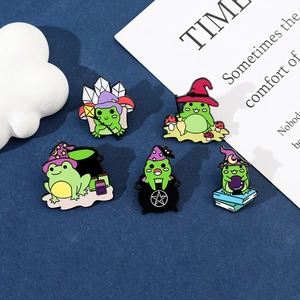 Detail view of five creative cartoon wizard frog enamel pins on a textured blue background