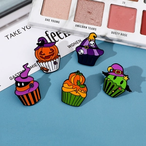 Macro shot of 5 Halloween cupcake enamel pins with pumpkin and skull designs on blue background