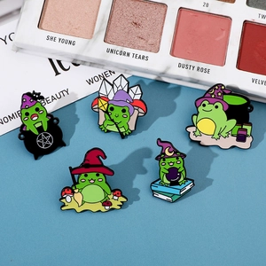 Set of five green enamel frog pins with magic wizard themes on a blue textured background