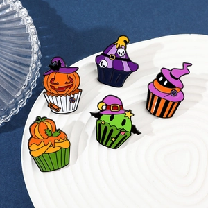 Detail of Halloween cupcake enamel pins with pumpkin and skull designs on a tray