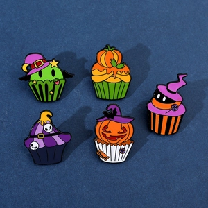 Flat lay detail of five Halloween cupcake enamel pins with pumpkins and skulls