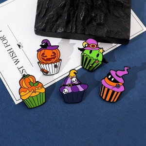Detail view of five Halloween enamel pins featuring cupcakes with pumpkins and skulls