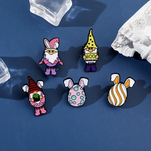 Gros plan de cinq épingles en émail festives avec de mignons gnomes et des œufs décorés